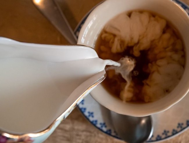 a pitcher of cream being poured into a tea cup