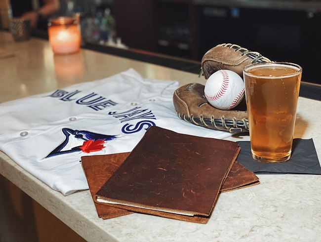 a baseball jersey, baseball and glove sitting on a bar with a glass of beer