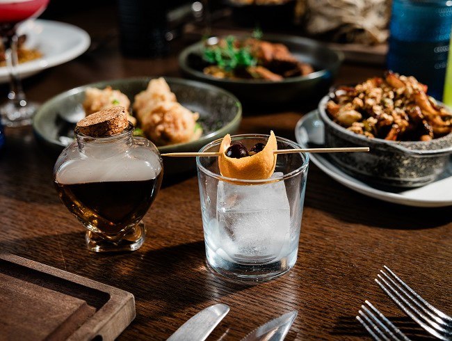 A glass with a toothpick on it next to a bottle of premium liquor at HEW Parlor & Chophouse